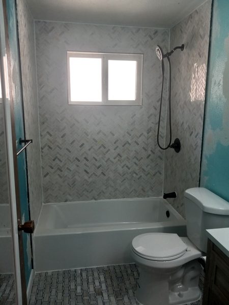 Bathroom with herringbone marble tile being installed, teal ceiling accent